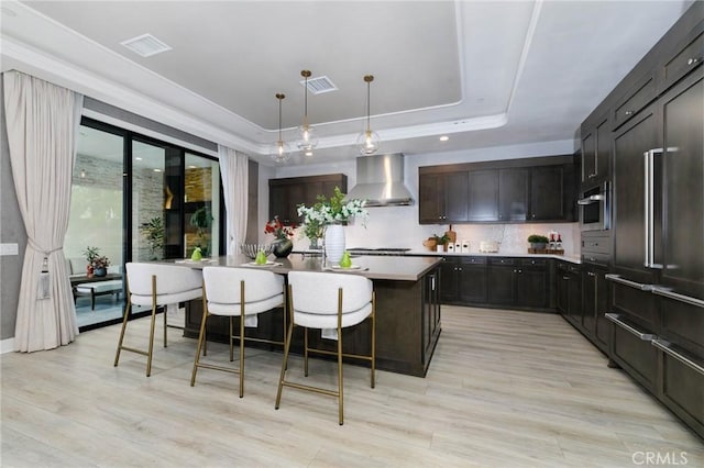 114 Interstellar, Irvine, CA 92618 - kitchen featuring wall chimney range hood, visible vents, light wood-style floors, light countertops, and a tray ceiling