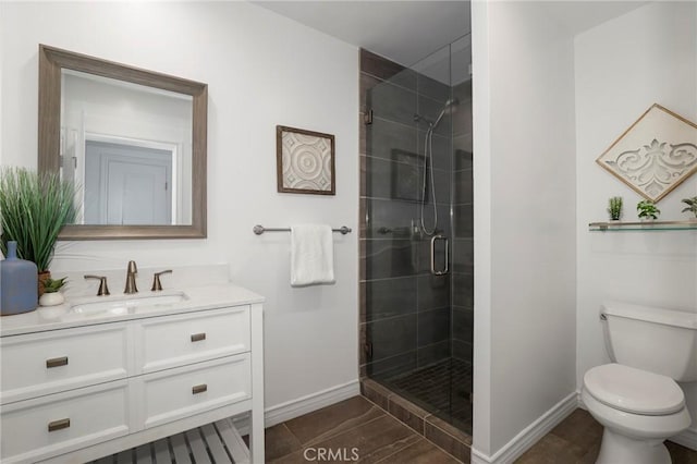 bathroom with vanity, toilet, baseboards, and a stall shower