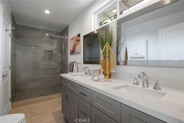 bathroom featuring a sink, a shower stall, toilet, and double vanity