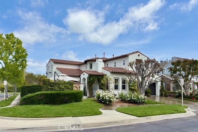 mediterranean / spanish house with a tiled roof, driveway, stucco siding, and a front yard