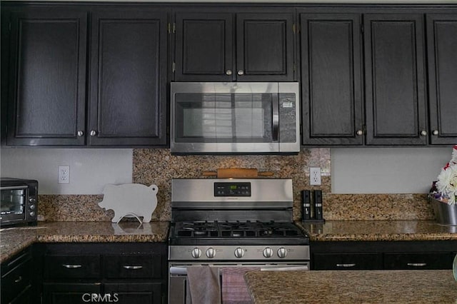 27069 Dawnview Ct, Corona, CA 92883 - kitchen featuring dark stone counters, dark cabinetry, stainless steel appliances, and a toaster
