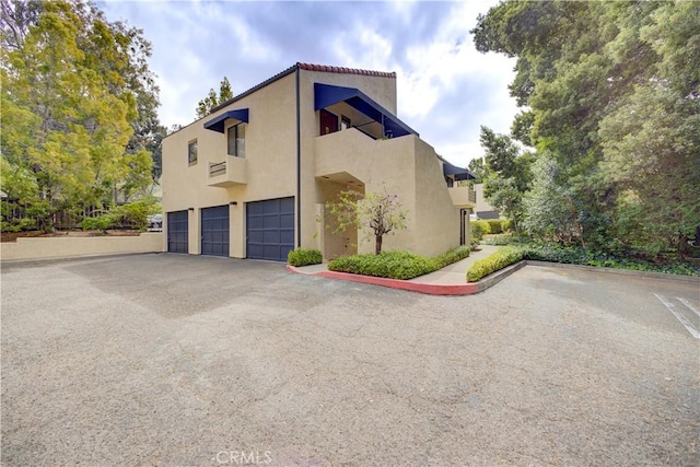view of side of home featuring a garage, stucco siding, and driveway