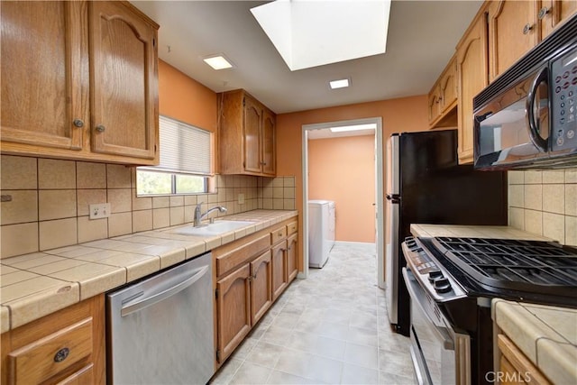 kitchen featuring a sink, a skylight, backsplash, and stainless steel appliances