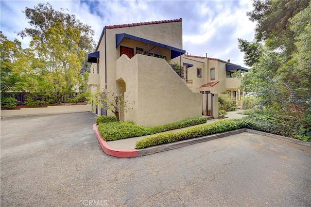 view of side of property with a tiled roof and stucco siding