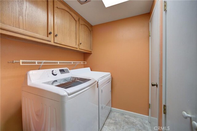laundry room with baseboards, cabinet space, a skylight, and washing machine and clothes dryer