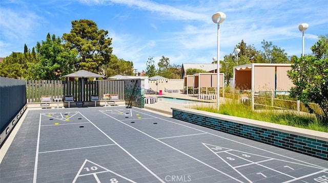 view of home's community with a pool, shuffleboard, and fence