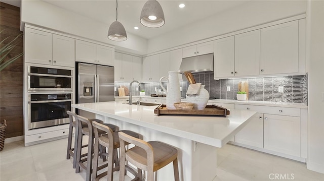 kitchen with white cabinets, a sink, appliances with stainless steel finishes, light countertops, and under cabinet range hood