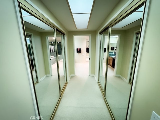 corridor featuring baseboards and light carpet