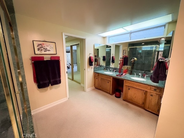 bathroom featuring double vanity, baseboards, a shower with door, and a sink