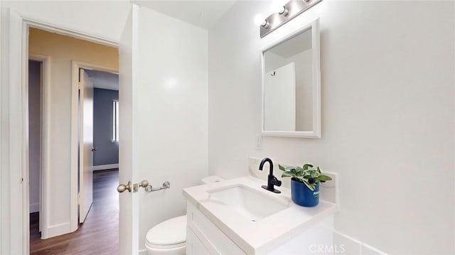 bathroom with wood finished floors, vanity, toilet, and baseboards