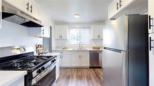 kitchen featuring a sink, stainless steel appliances, white cabinets, and under cabinet range hood