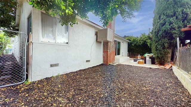 view of property exterior with crawl space, stucco siding, a fenced backyard, and a chimney