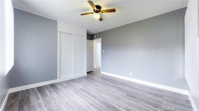unfurnished bedroom featuring visible vents, a closet, baseboards, light wood finished floors, and a ceiling fan