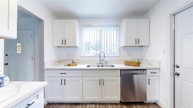 kitchen with white cabinets, light stone counters, dishwasher, and a sink