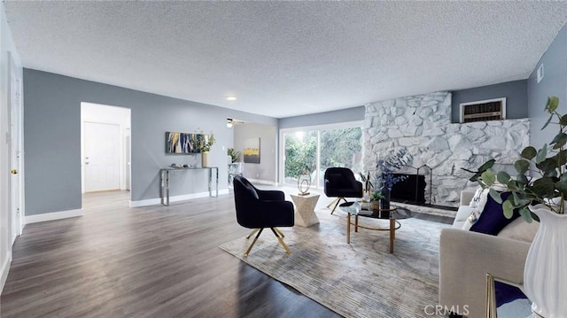 living area featuring a textured ceiling, baseboards, wood finished floors, and a fireplace