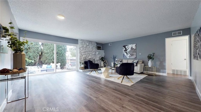 living room with a textured ceiling, visible vents, wood finished floors, and a fireplace