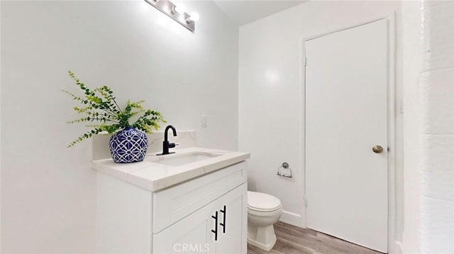 bathroom with wood finished floors, toilet, and vanity