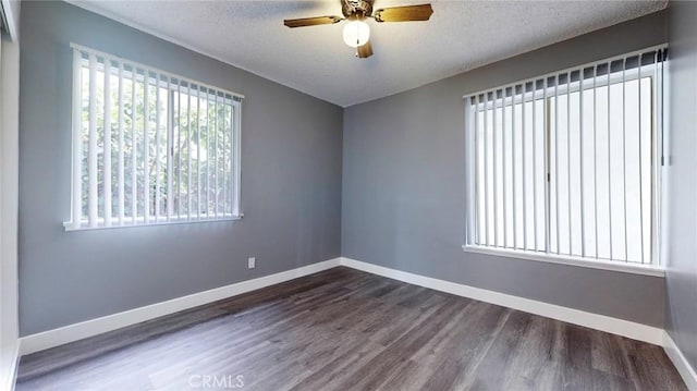 empty room with a textured ceiling, a ceiling fan, dark wood finished floors, and baseboards