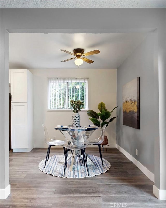 dining area with a ceiling fan, wood finished floors, and baseboards