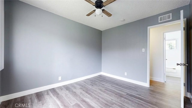 unfurnished room with baseboards, visible vents, wood finished floors, and a ceiling fan