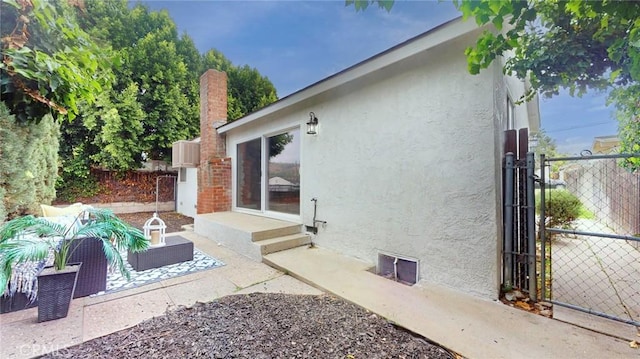view of home's exterior featuring a patio, a gate, a chimney, stucco siding, and fence
