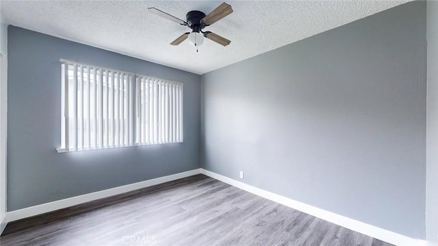 empty room featuring a textured ceiling, wood finished floors, ceiling fan, and plenty of natural light