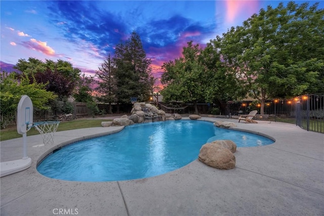 pool at dusk with fence, a patio, and a fenced in pool