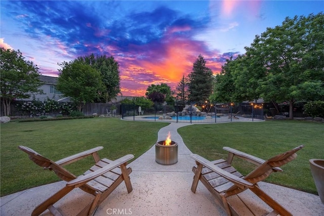 exterior space featuring a lawn, fence, an outdoor fire pit, and a pool