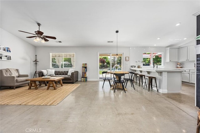 living area with recessed lighting, a ceiling fan, visible vents, baseboards, and finished concrete floors