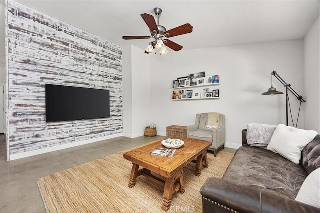 living room with finished concrete flooring, ceiling fan, and baseboards