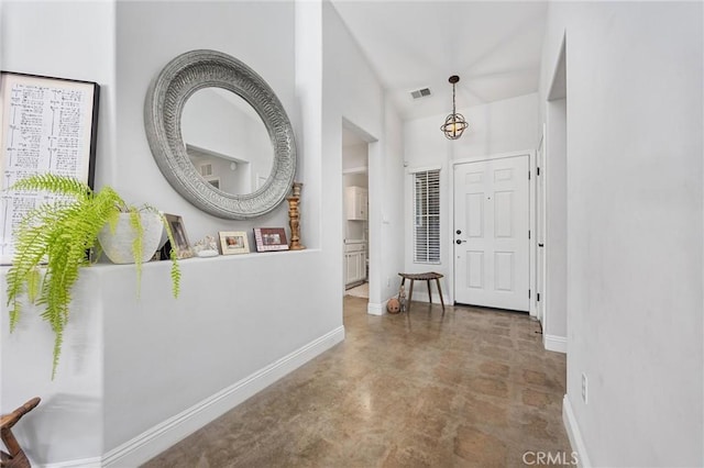 foyer entrance featuring baseboards, visible vents, and concrete floors