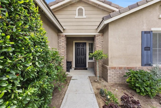 property entrance with brick siding and stucco siding