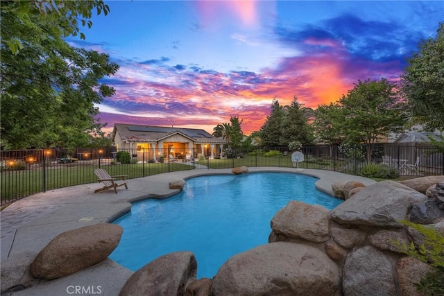 pool at dusk featuring a yard, fence, a fenced in pool, and a patio area
