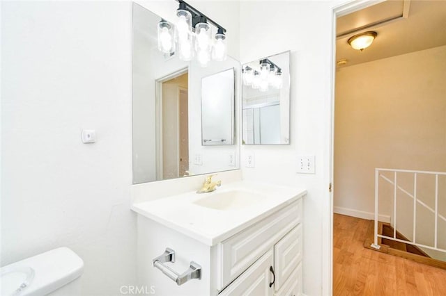 bathroom featuring wood finished floors, toilet, and vanity