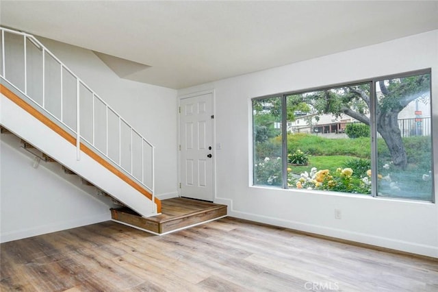 foyer with stairway, wood finished floors, and baseboards