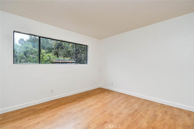 spare room with baseboards and light wood-style floors