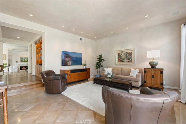 living area with recessed lighting, visible vents, a lit fireplace, and baseboards