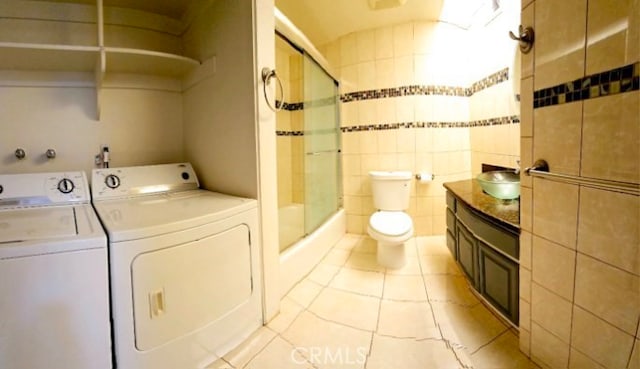 21040 Parthenia St Unit 13, Canoga Park, CA 91304 - bathroom with washing machine and clothes dryer, tile patterned flooring, toilet, a sink, and tile walls