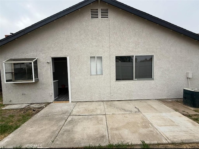 rear view of property featuring a patio, stucco siding, and central AC unit