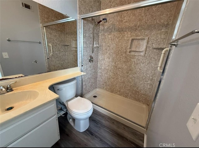 bathroom featuring visible vents, a shower stall, wood finished floors, vanity, and toilet