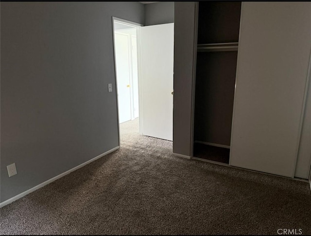 unfurnished bedroom featuring baseboards, carpet, and a closet