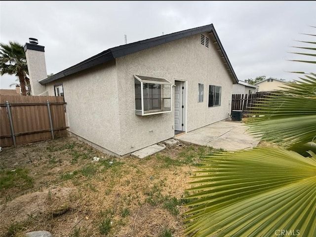 back of property with fence, a patio, and stucco siding