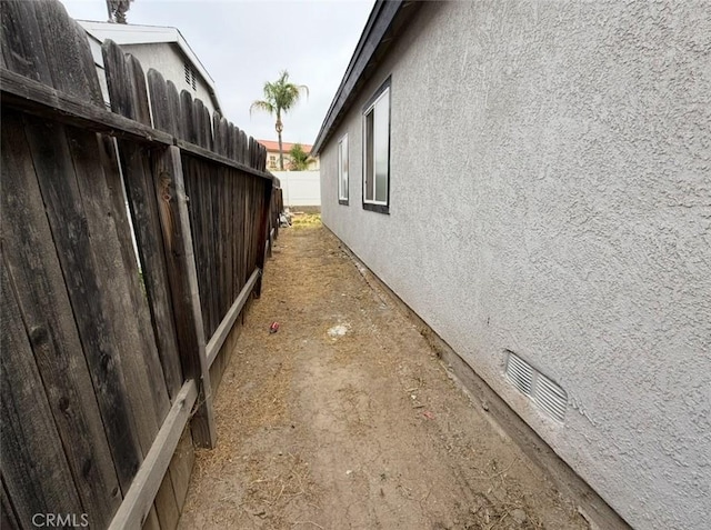 view of side of home featuring fence and stucco siding