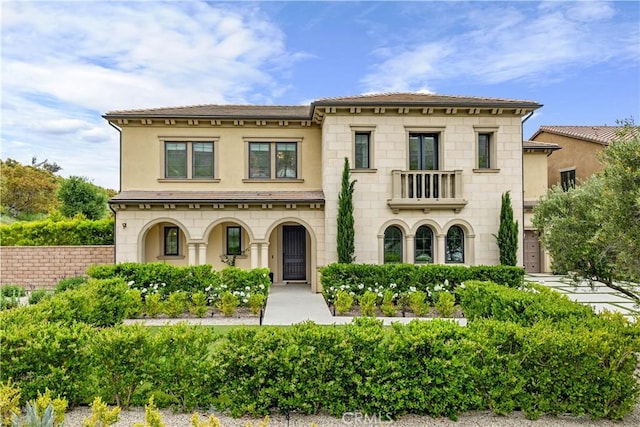 view of front of home featuring stone siding, stucco siding, and a balcony
