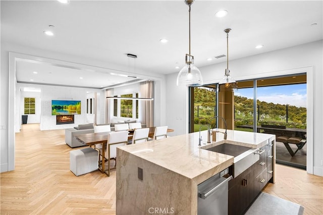 kitchen featuring stainless steel dishwasher, a healthy amount of sunlight, a sink, and a center island with sink