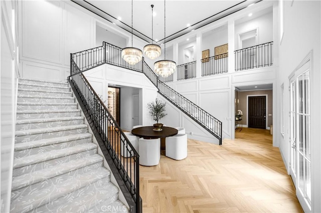 stairs featuring recessed lighting, a high ceiling, a chandelier, and a decorative wall