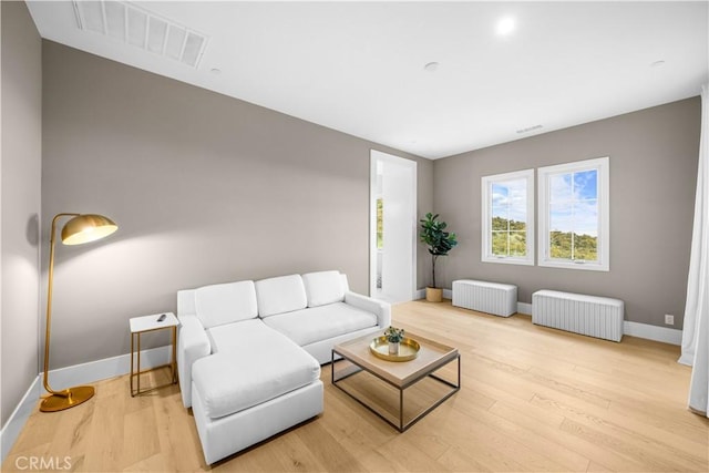 living room featuring visible vents, radiator, baseboards, and wood finished floors