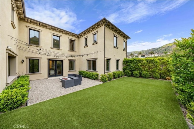 back of house with an outdoor living space, a mountain view, a yard, a patio, and stucco siding