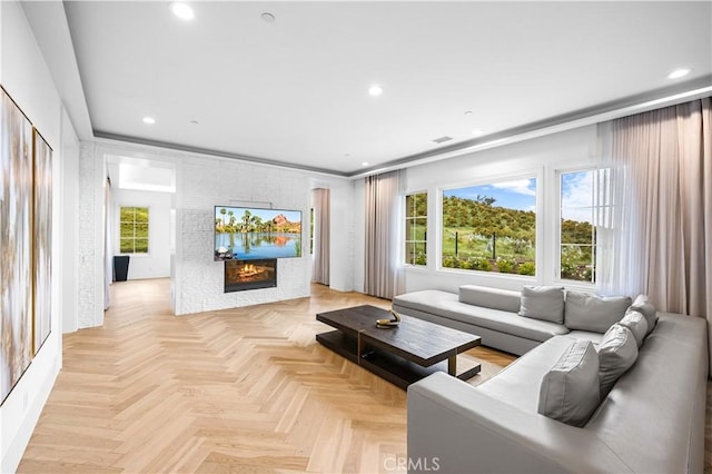 living room featuring recessed lighting, a glass covered fireplace, and visible vents