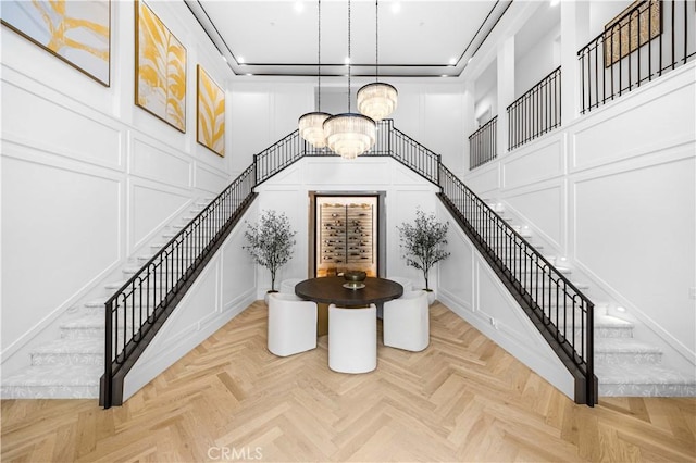entrance foyer featuring an inviting chandelier, stairway, and a decorative wall